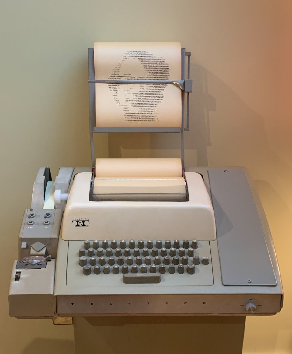 Picture of a Teletype Model 33, featuring a print-out of a face