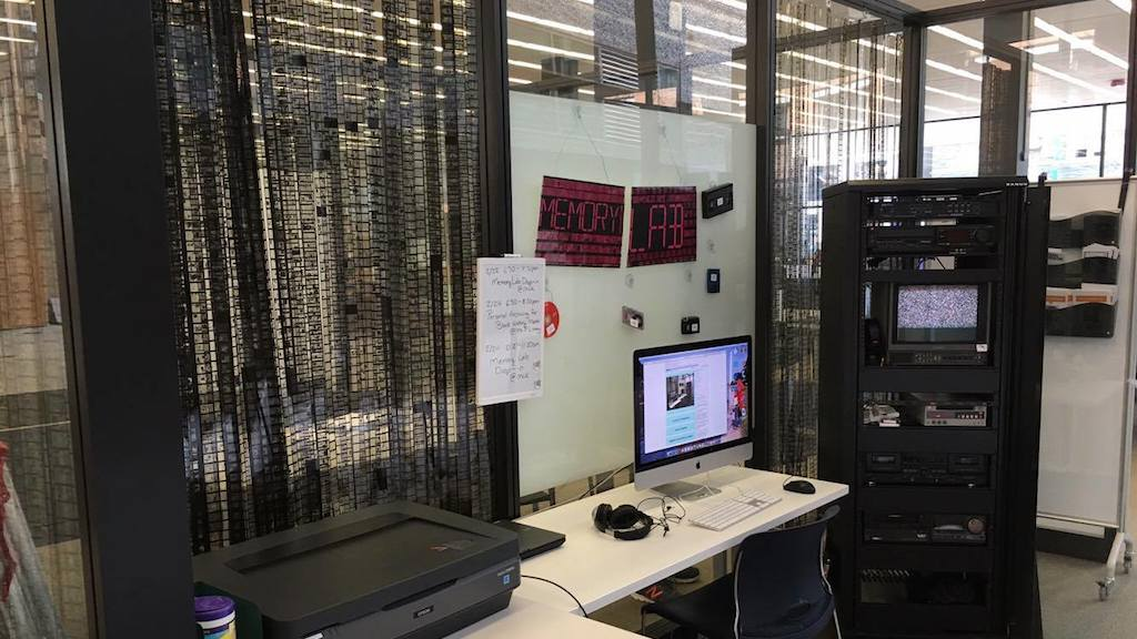 Photo of the DC Public Memory Lab, featuring a transfer rack, flatbed scanner, desk and dedicated workstation.